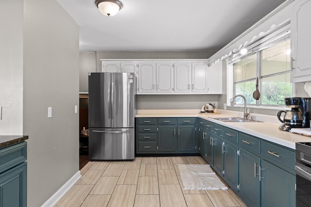 51 N Case Ave, Trenton, GA 30752 - kitchen with freestanding refrigerator, white cabinetry, a sink, wood tiled floors, and range