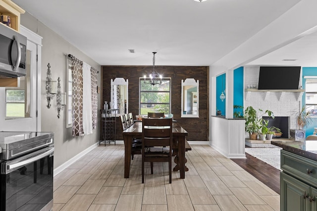 51 N Case Ave, Trenton, GA 30752 - dining space featuring a chandelier, baseboards, light wood-type flooring, a brick fireplace, and an accent wall