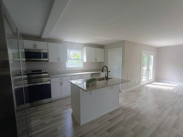 657 Chaffin Rd, Lafayette, TN 37083 - kitchen with appliances with stainless steel finishes, a sink, light wood-type flooring, white cabinetry, and a kitchen bar