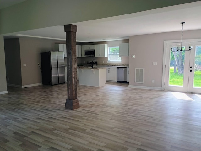 657 Chaffin Rd, Lafayette, TN 37083 - kitchen featuring appliances with stainless steel finishes, open floor plan, a kitchen bar, light wood-style flooring, and baseboards