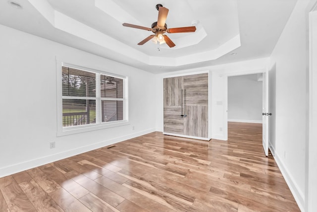 4510 Akin Rd, Cunningham, TN 37052 - unfurnished bedroom with a tray ceiling, wood finished floors, and a ceiling fan