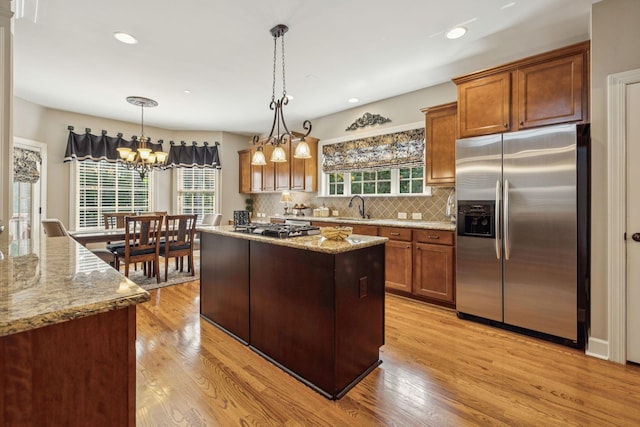 2064 Catalina Way, Nolensville, TN 37135 - kitchen with appliances with stainless steel finishes, light wood-style flooring, light stone counters, brown cabinetry, and backsplash