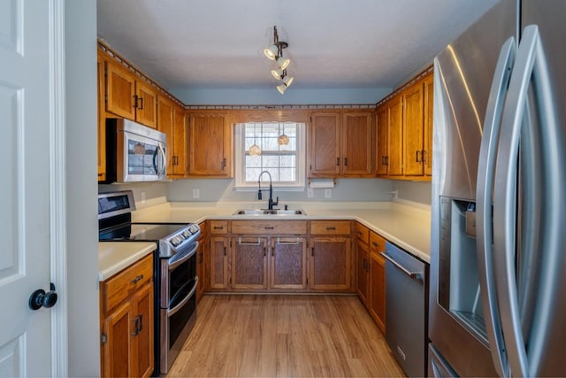 55 Bluebird Ln, Lafayette, TN 37083 - kitchen with stainless steel appliances, a sink, brown cabinetry, and light wood finished floors