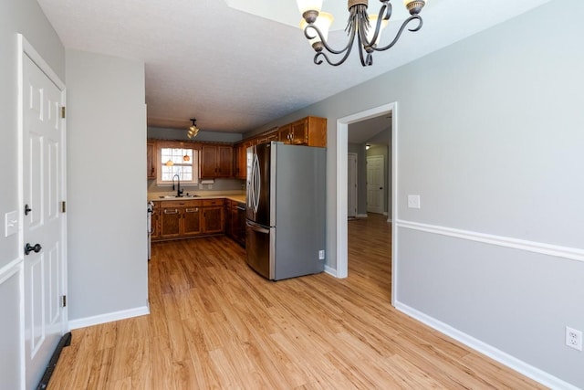 55 Bluebird Ln, Lafayette, TN 37083 - kitchen featuring freestanding refrigerator, a sink, a chandelier, light wood-style floors, and baseboards