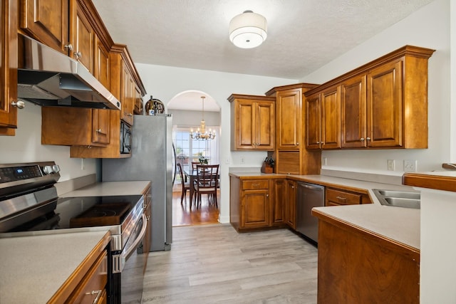 2056 Earl Pearce Cir, Mount Juliet, TN 37122 - kitchen with stainless steel appliances, under cabinet range hood, light wood-style flooring, a chandelier, and brown cabinetry