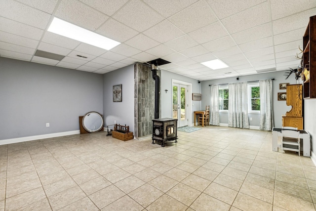 1064 Bills Ln, Joelton, TN 37080 - below grade area with a wood stove, a paneled ceiling, baseboards, and light tile patterned floors