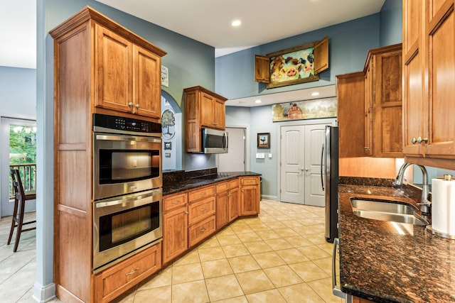 1064 Bills Ln, Joelton, TN 37080 - kitchen with a sink, appliances with stainless steel finishes, light tile patterned floors, brown cabinetry, and dark stone countertops