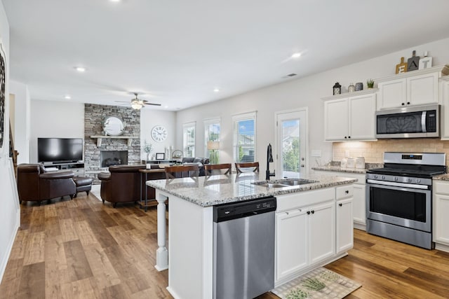 1045 Brayden Dr, Fairview, TN 37062 - kitchen with stainless steel appliances, a sink, ceiling fan, a fireplace, and a center island with sink