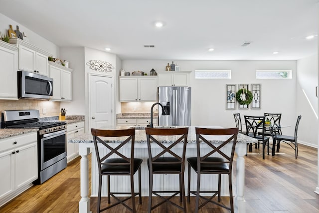 1045 Brayden Dr, Fairview, TN 37062 - kitchen with stainless steel appliances, a sink, a breakfast bar, decorative backsplash, and recessed lighting