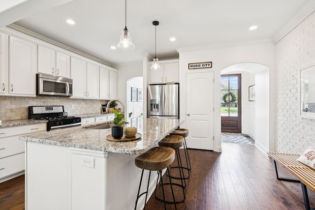 1074 Cantwell Pl, Spring Hill, TN 37174 - kitchen featuring appliances with stainless steel finishes, arched walkways, a sink, decorative backsplash, and ornamental molding