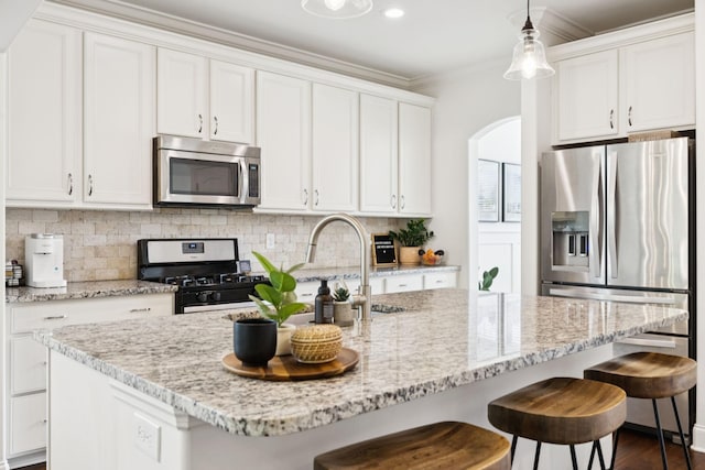 1074 Cantwell Pl, Spring Hill, TN 37174 - kitchen with stainless steel appliances, arched walkways, white cabinets, decorative backsplash, and ornamental molding