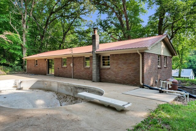 5595 Denmark Rd, Erin, TN 37061 - back of property featuring a patio, brick siding, metal roof, and a chimney