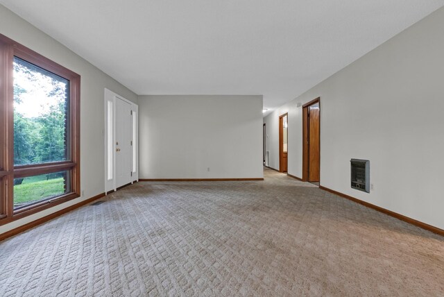 5595 Denmark Rd, Erin, TN 37061 - spare room featuring heating unit, light colored carpet, baseboards, and a fireplace
