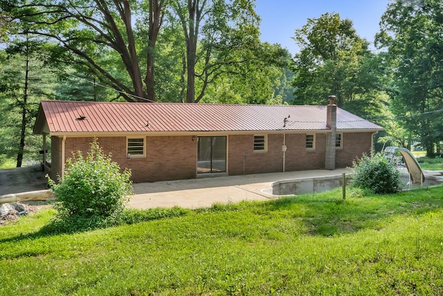 5595 Denmark Rd, Erin, TN 37061 - back of property featuring metal roof, a chimney, a patio area, and brick siding