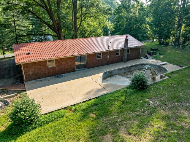 5595 Denmark Rd, Erin, TN 37061 - back of property with metal roof, brick siding, a patio area, a yard, and an empty pool