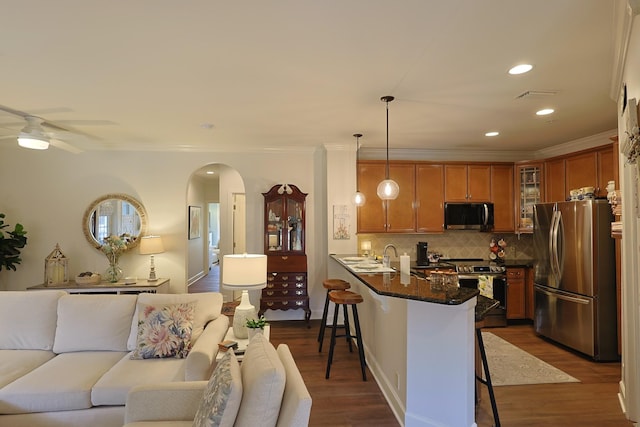 307 Seven Springs Way Unit 304, Brentwood, TN 37027 - kitchen with stainless steel appliances, a breakfast bar area, arched walkways, brown cabinetry, and open floor plan