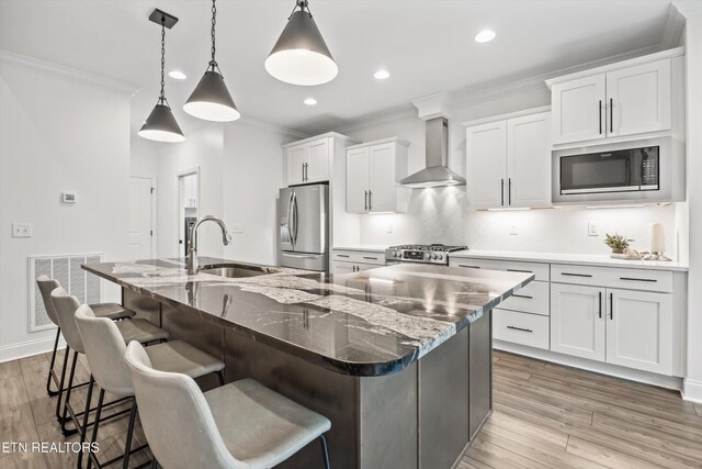 9327 Paradise Valley Ln, Knoxville, TN 37922 - kitchen featuring stainless steel appliances, wall chimney exhaust hood, ornamental molding, a kitchen island with sink, and white cabinets