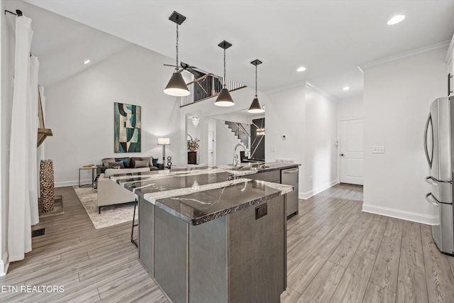 9327 Paradise Valley Ln, Knoxville, TN 37922 - kitchen with appliances with stainless steel finishes, a center island with sink, crown molding, dark stone counters, and light wood-style flooring