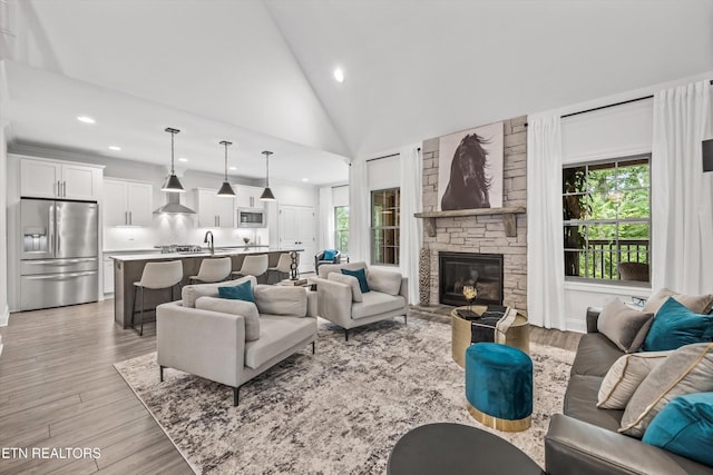 9327 Paradise Valley Ln, Knoxville, TN 37922 - living room featuring recessed lighting, plenty of natural light, light wood finished floors, a stone fireplace, and high vaulted ceiling
