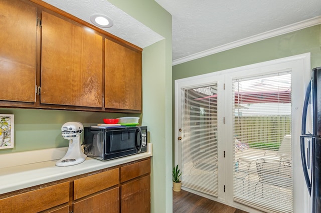213 Cedarwood Ln, Madison, TN 37115 - kitchen with black microwave, light countertops, crown molding, dark wood-style flooring, and freestanding refrigerator
