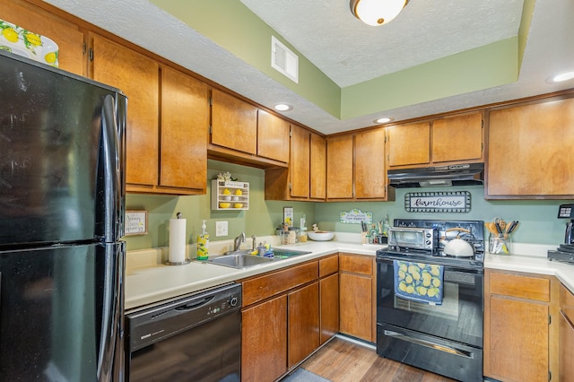 213 Cedarwood Ln, Madison, TN 37115 - kitchen with black appliances, under cabinet range hood, a sink, brown cabinetry, and wood finished floors