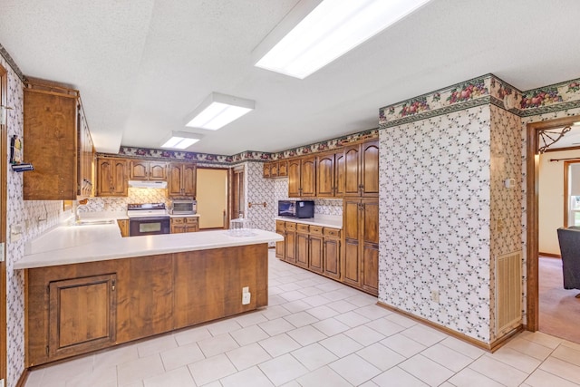 220 Winton Way Rd, Manchester, TN 37355 - kitchen with range with electric stovetop, wallpapered walls, black microwave, a peninsula, and light countertops