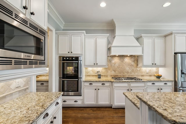 1577 Westhaven Blvd, Franklin, TN 37064 - kitchen featuring stainless steel appliances, tasteful backsplash, wall chimney exhaust hood, light stone counters, and crown molding