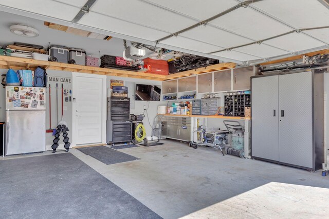 1240 Hensfield Dr, Murfreesboro, TN 37128 - garage featuring freestanding refrigerator, a garage door opener, and a workshop area