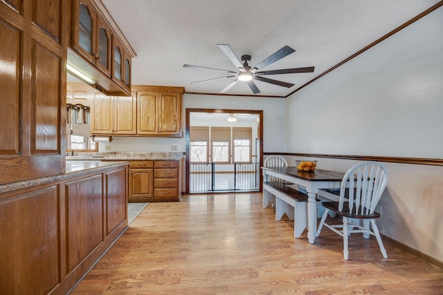 239 Henry Bayless Rd, Ardmore, TN 38449 - kitchen with ceiling fan, brown cabinets, light wood finished floors, glass insert cabinets, and a textured ceiling