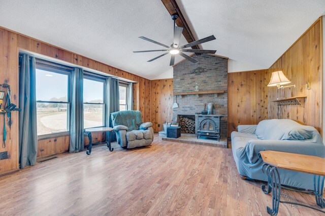 239 Henry Bayless Rd, Ardmore, TN 38449 - living area featuring wood walls, light wood-type flooring, a ceiling fan, a wood stove, and a textured ceiling
