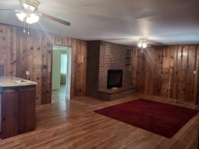 166 Westview St, Camden, TN 38320 - unfurnished living room with a ceiling fan, wood finished floors, wooden walls, and a brick fireplace