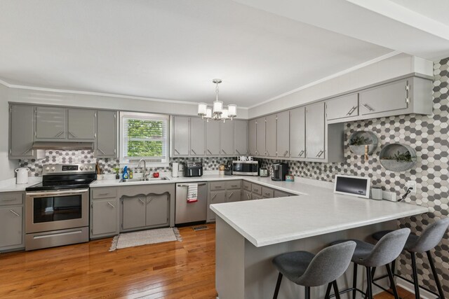 307 S Hummingbird Ln, Dickson, TN 37055 - kitchen with stainless steel appliances, gray cabinetry, a sink, crown molding, and a peninsula