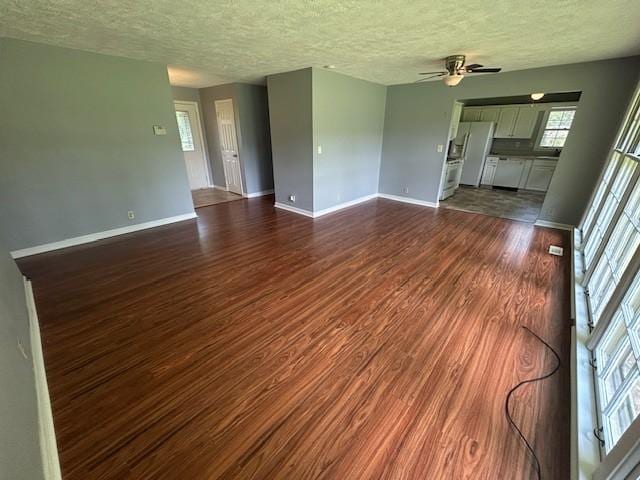 203 Arnold Ave, Tullahoma, TN 37388 - unfurnished living room featuring dark wood-style flooring, baseboards, ceiling fan, and a textured ceiling