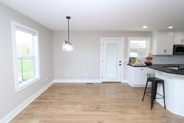 214 Miller Rd, Lafayette, TN 37083 - kitchen featuring stainless steel microwave, dark countertops, white cabinets, baseboards, and tasteful backsplash