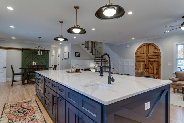 103 Maple St, Smyrna, TN 37167 - kitchen with a barn door, open floor plan, a sink, crown molding, and light wood-style floors