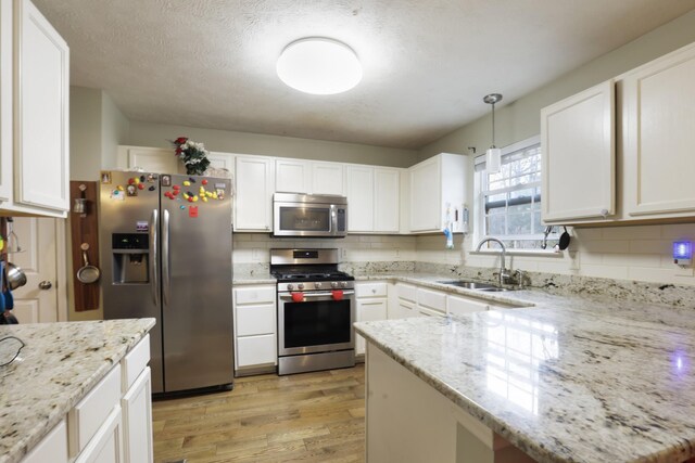 304 Baronswood Dr, Nolensville, TN 37135 - kitchen featuring stainless steel appliances, a sink, light wood-style flooring, decorative backsplash, and white cabinetry