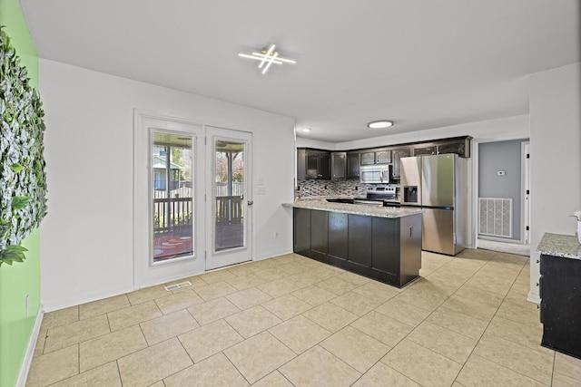 5009 Lanier Dr, Greenbrier, TN 37073 - kitchen featuring appliances with stainless steel finishes, a peninsula, decorative backsplash, light tile patterned floors, and light stone countertops
