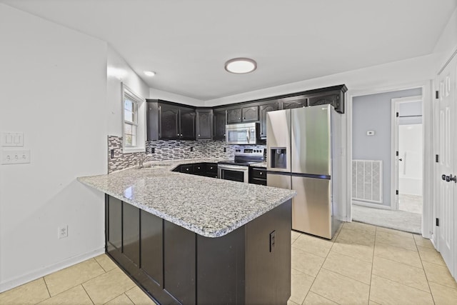 5009 Lanier Dr, Greenbrier, TN 37073 - kitchen with stainless steel appliances, a peninsula, decorative backsplash, light tile patterned flooring, and light stone counters