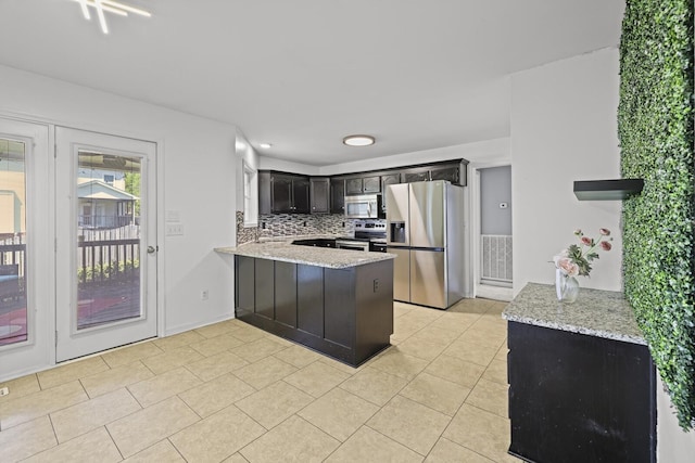 5009 Lanier Dr, Greenbrier, TN 37073 - kitchen featuring appliances with stainless steel finishes, a peninsula, decorative backsplash, and light stone counters