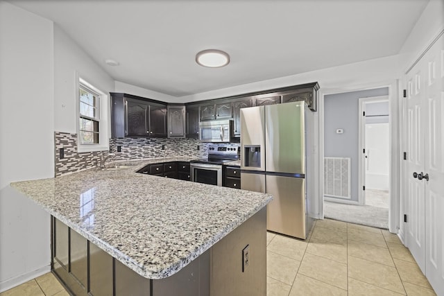 5009 Lanier Dr, Greenbrier, TN 37073 - kitchen featuring appliances with stainless steel finishes, a peninsula, tasteful backsplash, light stone counters, and light tile patterned floors