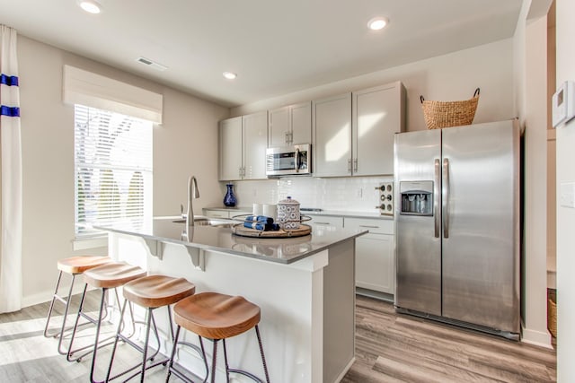 2413 Williams Ridge Dr, Columbia, TN 38401 - kitchen with appliances with stainless steel finishes, light wood-type flooring, an island with sink, a sink, and tasteful backsplash