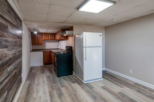 930 Havenhill Dr, Nashville, TN 37217 - kitchen with black range with gas stovetop, freestanding refrigerator, ventilation hood, wood finished floors, and dark countertops