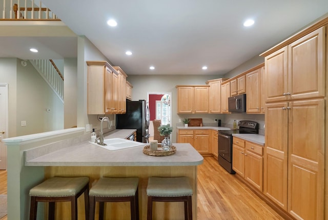 1513 Bunbury Dr, Thompsons Station, TN 37179 - kitchen with black appliances, a sink, light brown cabinetry, a breakfast bar, and a peninsula