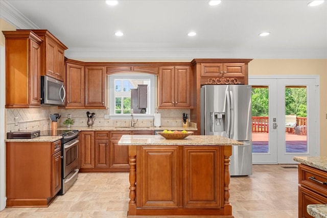 1446 Kittrell Rd, Franklin, TN 37064 - kitchen with stainless steel appliances, french doors, light stone countertops, brown cabinetry, and crown molding