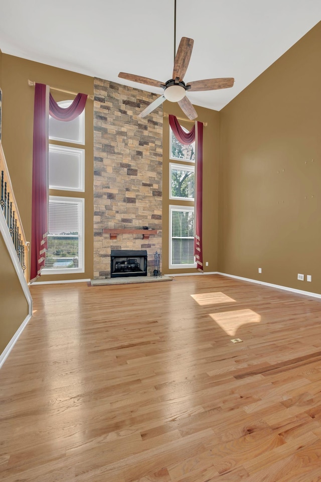 2005 Dunedin Cv, Old Hickory, TN 37138 - unfurnished living room with a stone fireplace, light wood finished floors, a ceiling fan, stairs, and a high ceiling