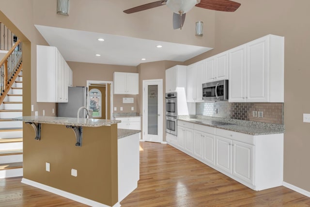 2005 Dunedin Cv, Old Hickory, TN 37138 - kitchen with appliances with stainless steel finishes, a peninsula, a ceiling fan, a kitchen breakfast bar, and decorative backsplash