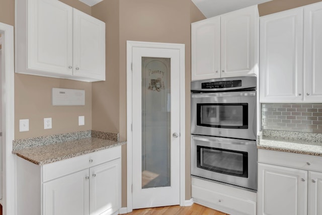 2005 Dunedin Cv, Old Hickory, TN 37138 - kitchen with stainless steel double oven, white cabinetry, tasteful backsplash, light stone counters, and light wood-type flooring