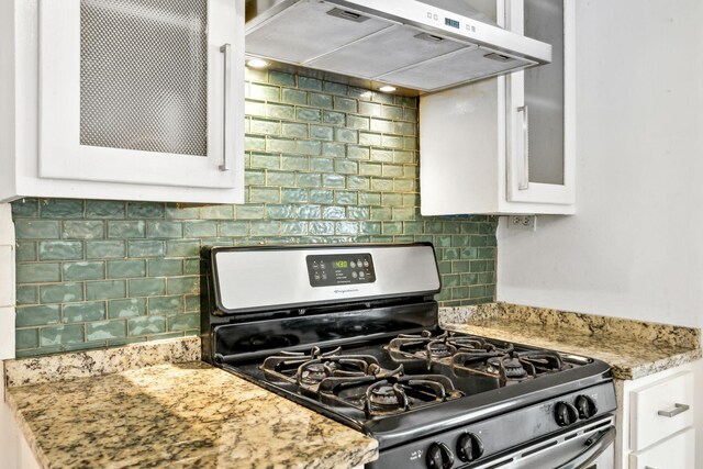 1306 Maymont Dr, Murfreesboro, TN 37130 - kitchen with gas stove, under cabinet range hood, white cabinetry, glass insert cabinets, and tasteful backsplash