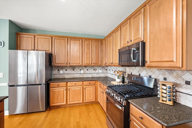 4055 Williford Way, Spring Hill, TN 37174 - kitchen with stainless steel appliances, light wood-style flooring, dark stone counters, and backsplash