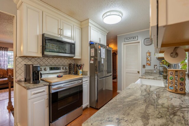 711 Hurricane Hill Dr, Waynesboro, TN 38485 - kitchen with appliances with stainless steel finishes, a sink, a textured ceiling, light wood-type flooring, and decorative backsplash